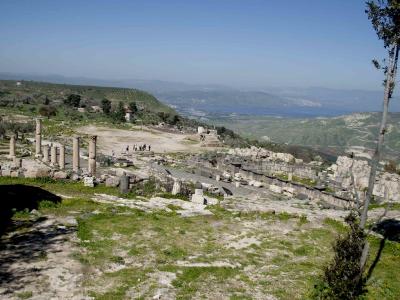 Rovine del ninfeo (in basalto) e della scala di accesso al complesso della basilica (pietra calcarea). Sullo sfondo si vedono il monte Tabor (a sinistra), il lago e la città di Tiberiade (al centro), i colli dell'alta Galilea.